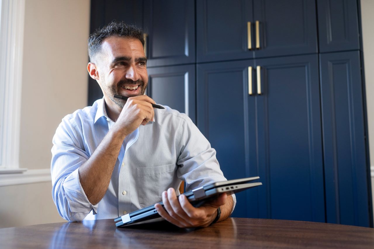 Man sitting at a table with a tablet, smiling.