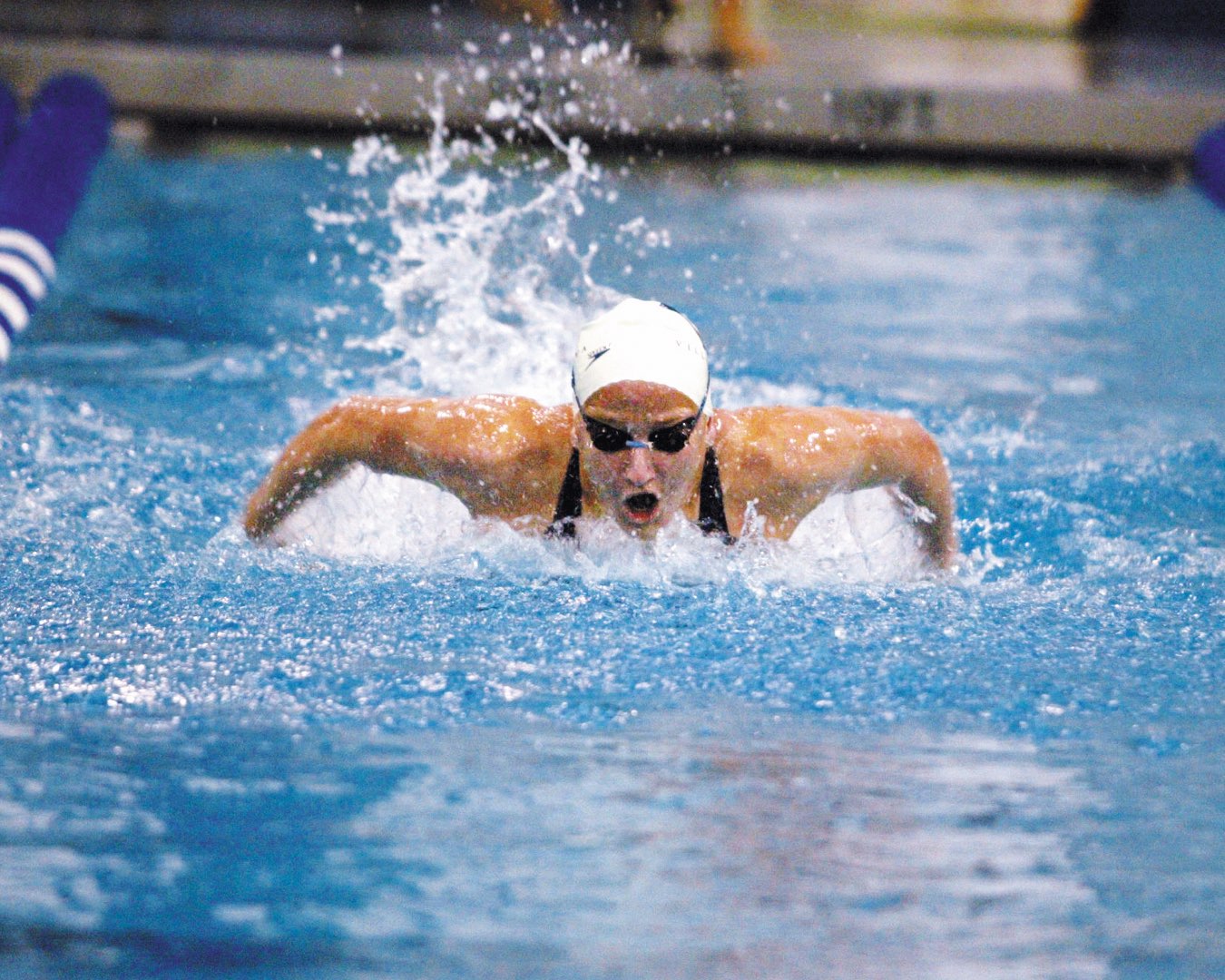 Water ripples behind a Villanova Women’s Swimming and Diving team member in her cap and goggles, as she speeds down the lane 