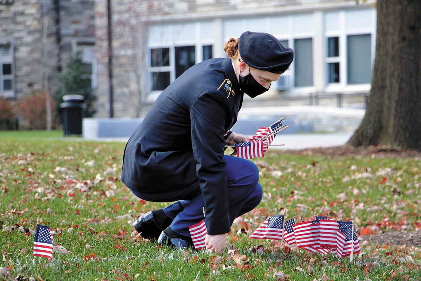 Female in military attire plants American flags on Villanova's campus