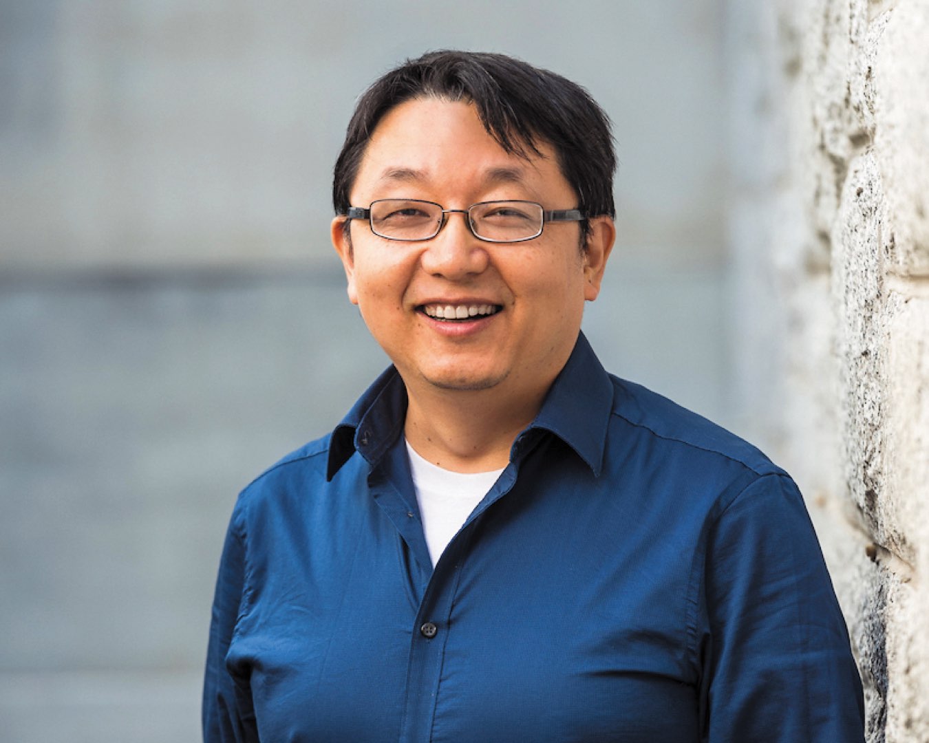 Headshot of Dr. Qianhong Wu wearing glasses and a blue dress shirt unbuttoned, smiling