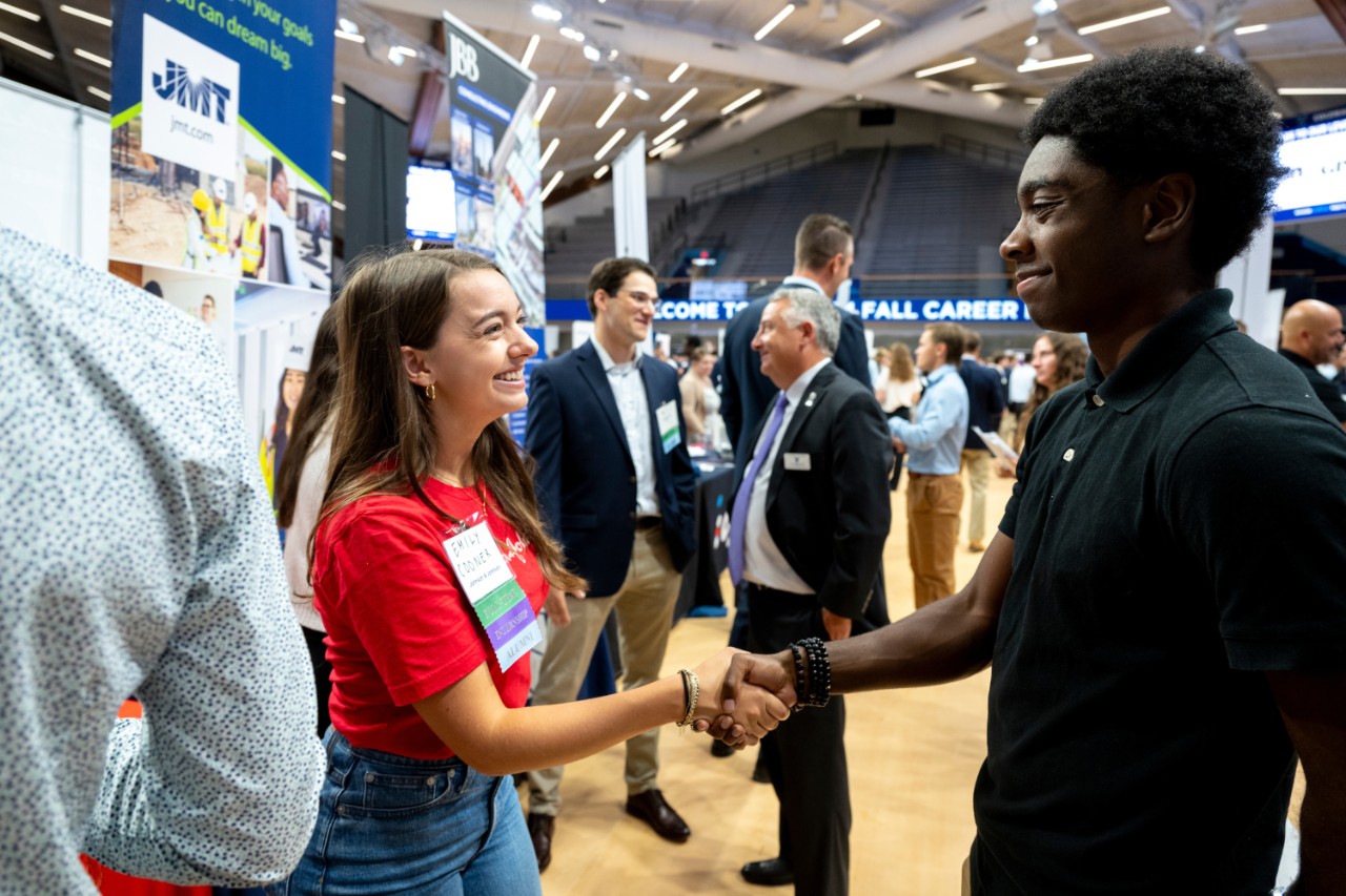 An employer shaking a students hand at a career event.