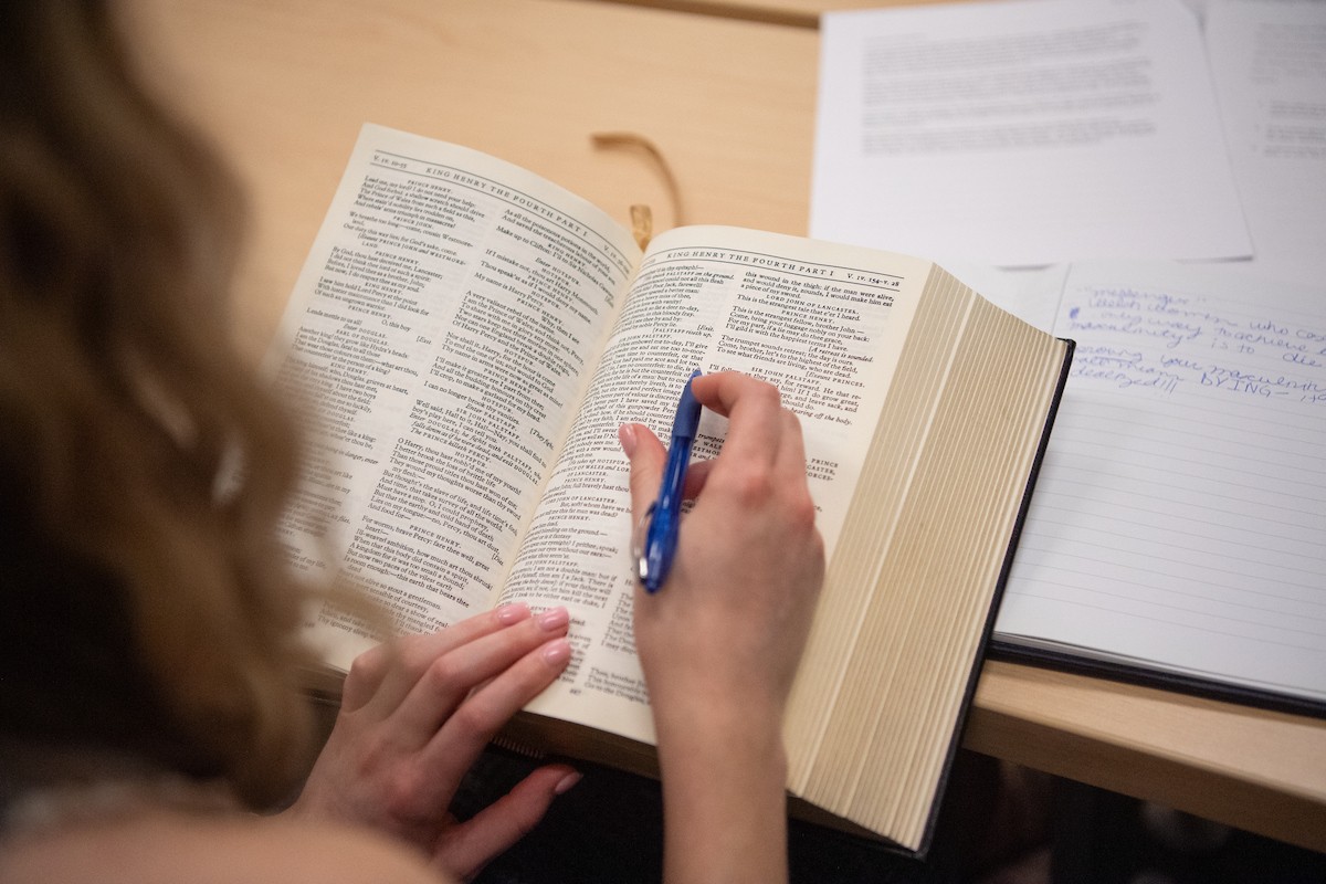 Student studying with a book and pen.