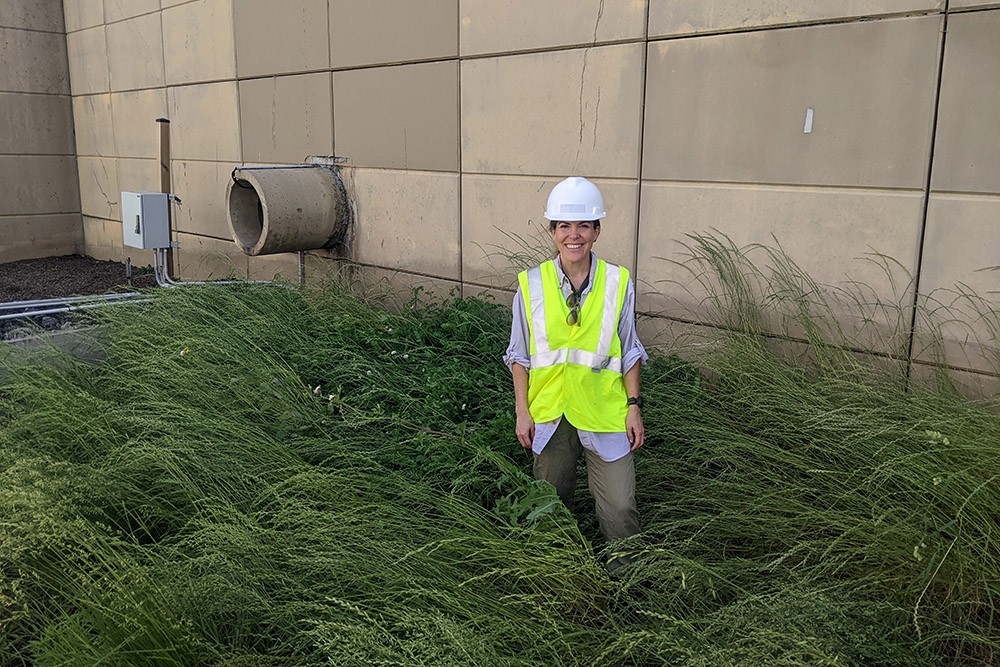 Virginia Smith, PhD, Assistant Professor, Department of Civil and Environmental Engineering Virginia Smith, PhD, standing in tall grassy area near a concrete wall