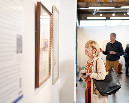 Patrons look at a piece at the exhibit, "Abstract Activism: Sam Maitin's Philadelphia."