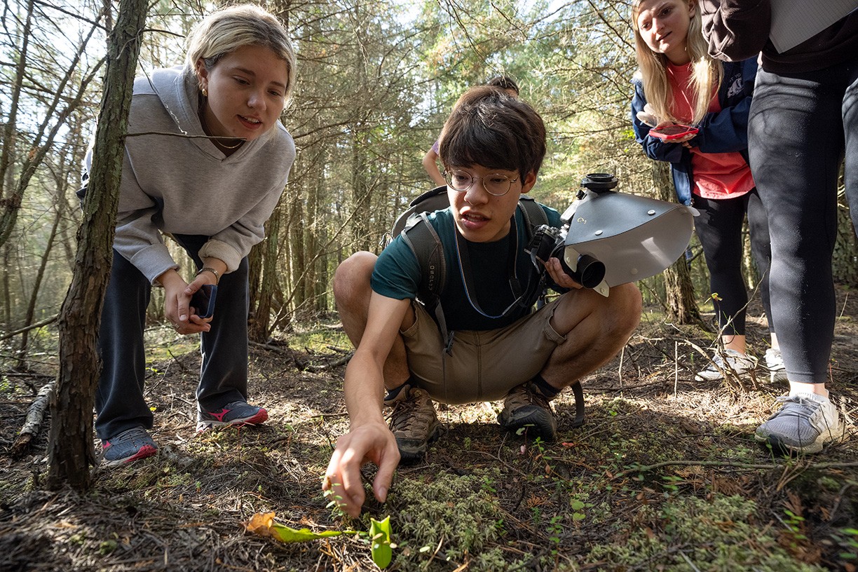 Carter Young evaluates plant life in a field, alongside his classmates.