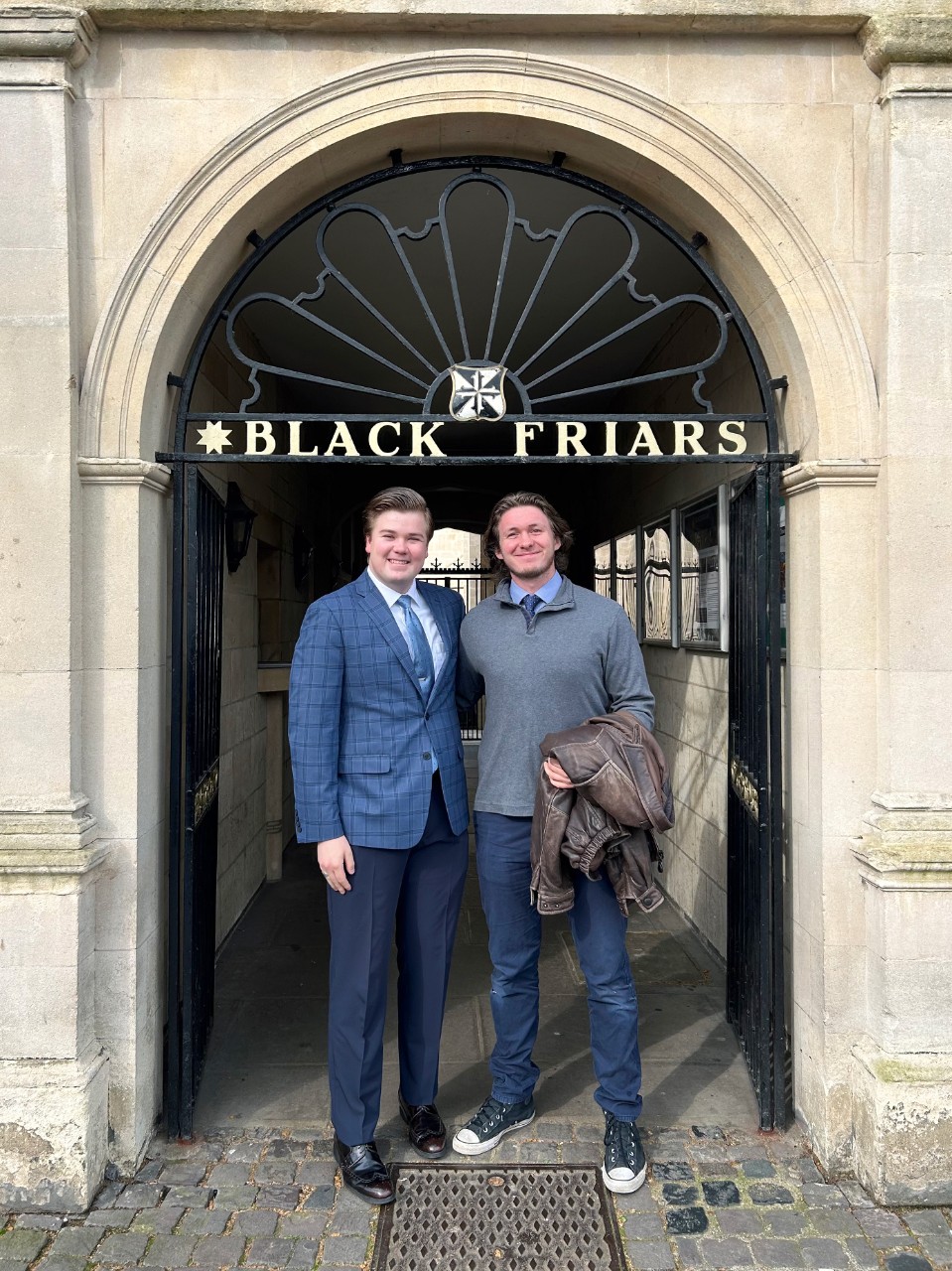 Student stands outside a Blackfriars sign in Oxford.