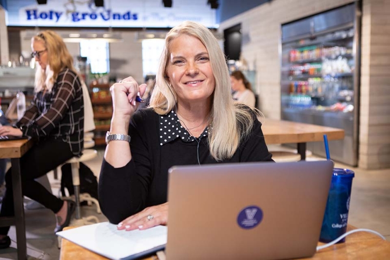 Shelby Myers doing schoolwork at her laptop at the coffee shop on campus