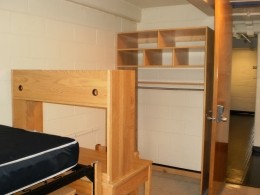 View of a bed, desk and open closet in a Stanford Hall double room.