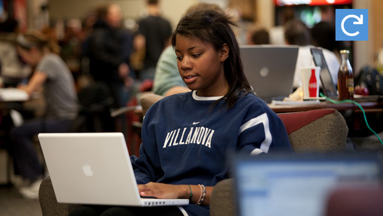Female tudent is working on laptop in cafeteria.