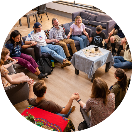 Individuals sitting in a circle holding hands