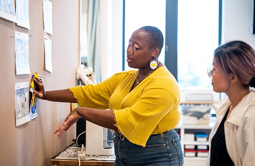 Veshonte Brown holds a swatch of fabric against a photo tacked to the wall in the Mullen Center's Costume Shop