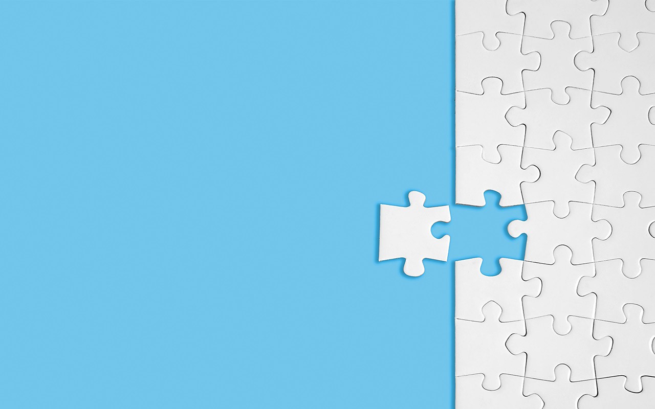 a white puzzle on a blue background has one piece left to complete it