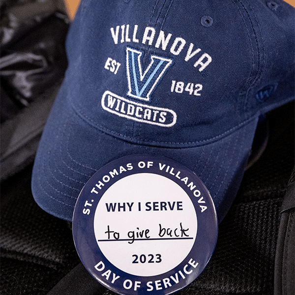 Blue Villanova cap pictured with a St. Thomas of Villanova Day of Service button