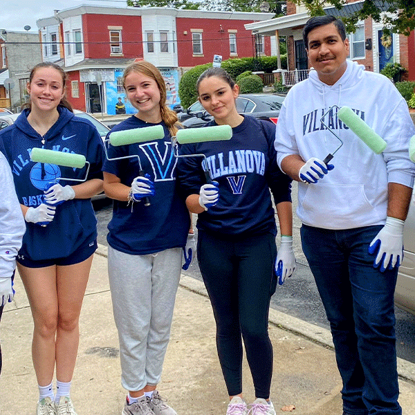 Four Villanova volunteers pose with their paint rollers