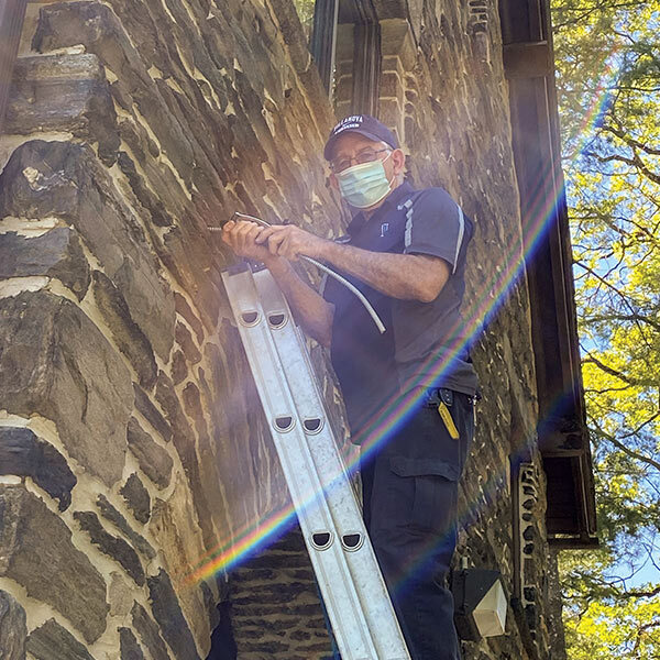 man outside standing on a ladder looking down 